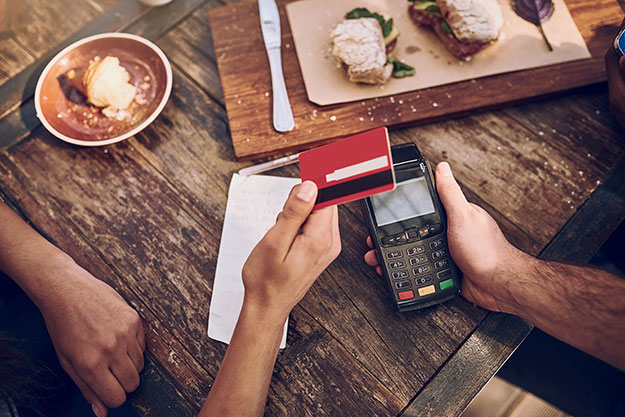 Person paying for a meal by tapping their credit card to the credit card reader